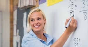 Female teacher smiling and writing on a white board