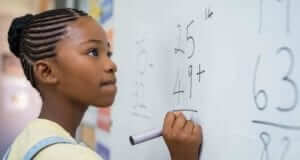 Young girl doing math problem on white board