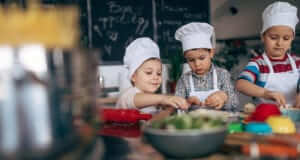 Children in culinary class with white chef hats.