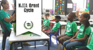 Children sitting in a classroom wearing green t-shirts with recycling symbol
