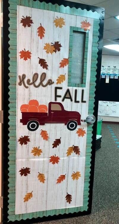 Classroom door that says "Hello Fall" with orange/brown/yellow leaves falling and an old brown pickup truck in the middle with orange pumpkins in the bed