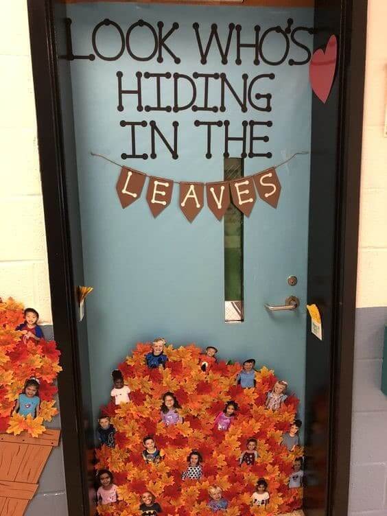 Classroom door that reads "Look who's hiding in the leaves" with students' pictures mixed in with leaves at the bottom