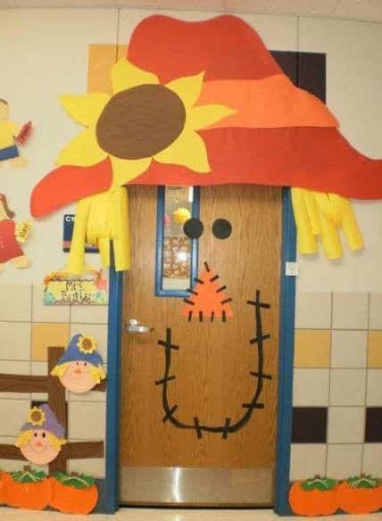 Classroom door decorated as a scarecrow with a big hat that has a sunflower on it