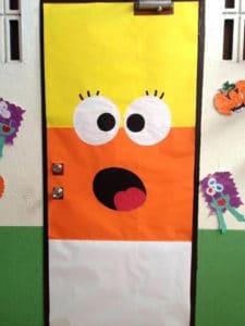 Classroom door decorated as candy-corn with a smiley face that looks suprised