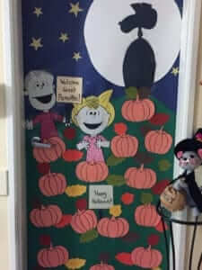 Classroom door with Charlie Brown characters and pumpkins in a field at night with spooky shadow in moon