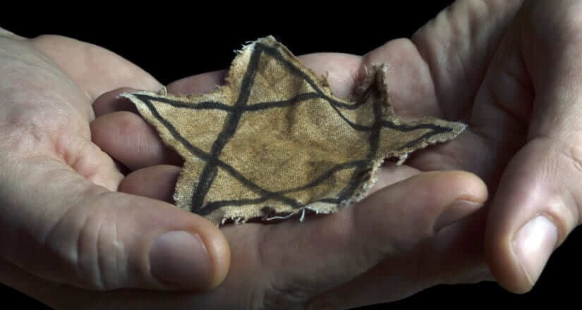 One hand over the other holding a piece of fabric with the Star of David on it