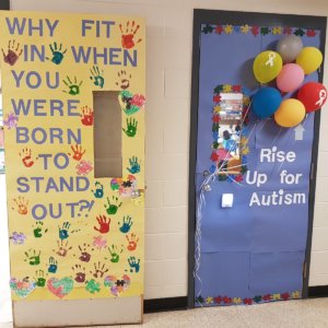 Two classroom doors decorated. One says "Why fit in when you were born to stand out" with students' hand prints on it and the other says "Rise up for Austism" with multi-colored puzzle pieces and balloons attached