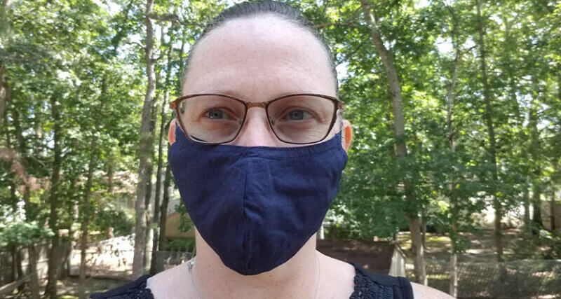 Head shot of Caitlin Gioe in the woods wearing a surgical mask
