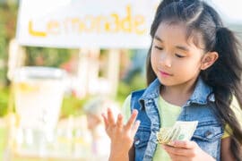 Little girl counting money at a lemonade stand